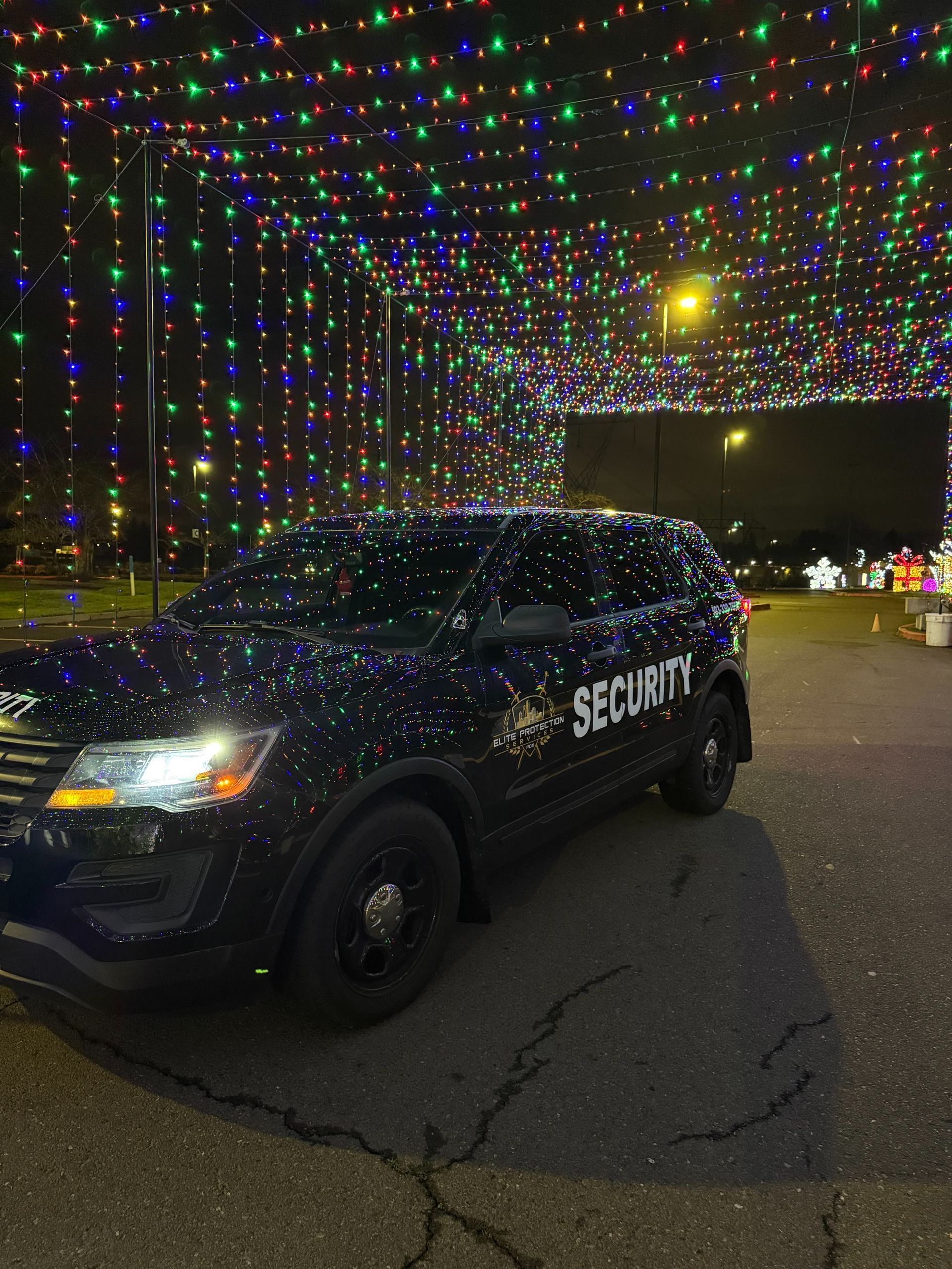 Security vehicle parked under colorful holiday lights at night