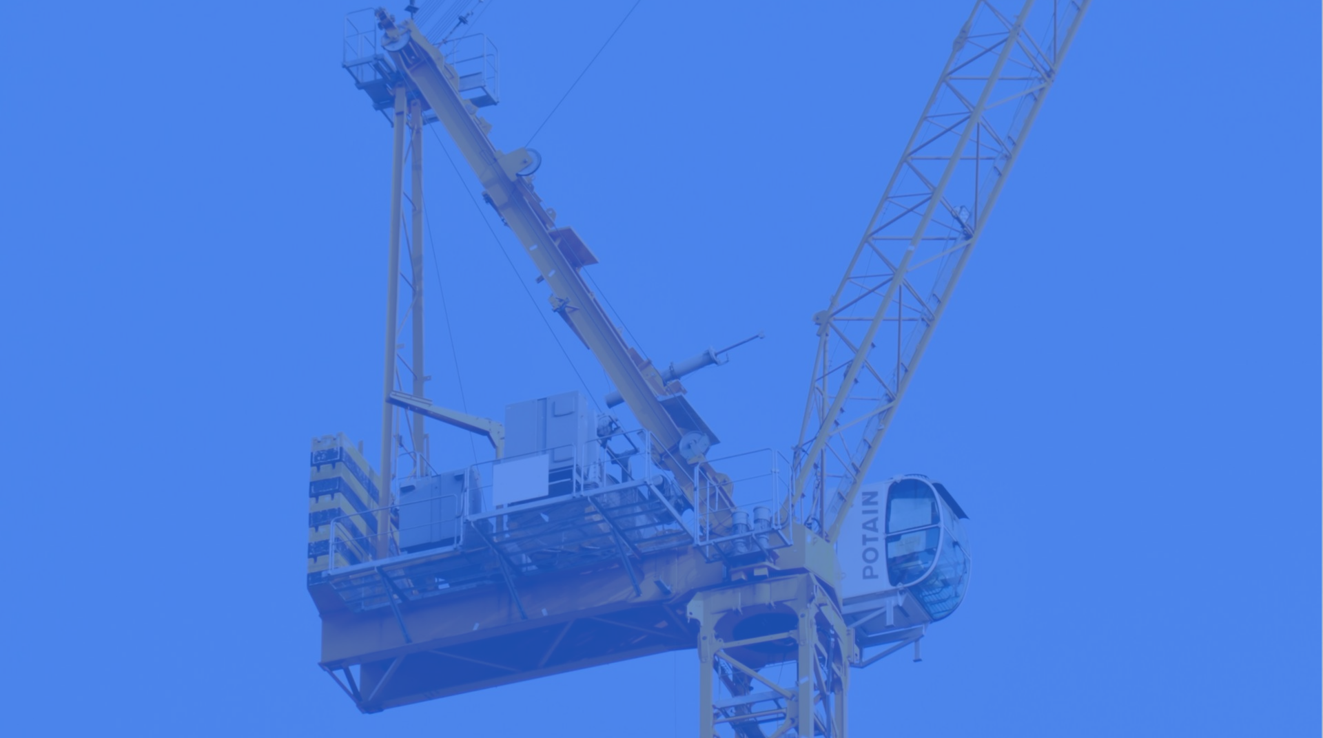 Blue-tinted construction crane lifting a suspended platform against the sky