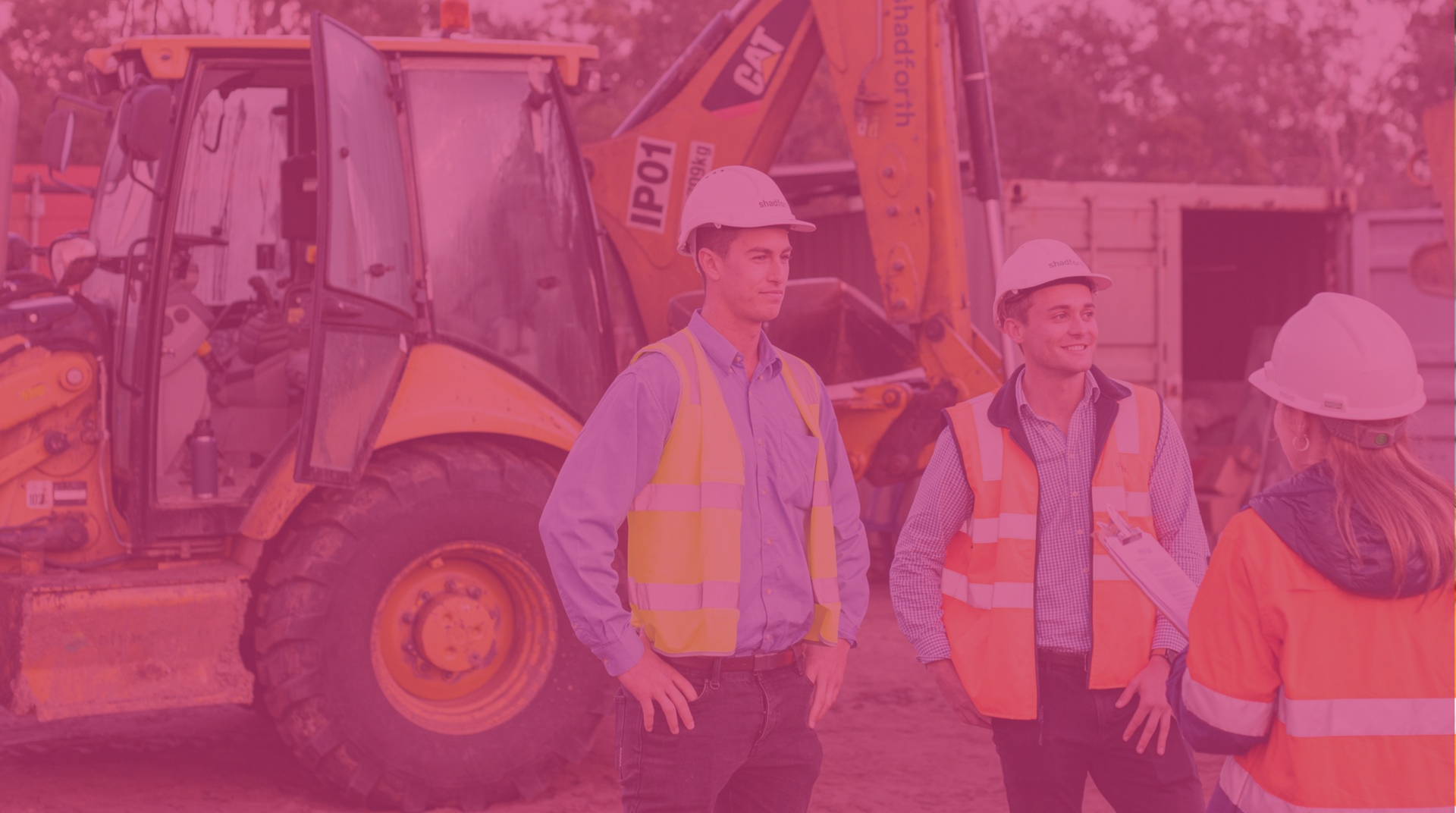 Construction workers in hard hats and safety vests talk beside a backhoe at a work site.