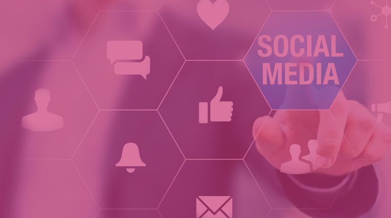 Hand touching glowing social media icons and “SOCIAL MEDIA” text on pink background