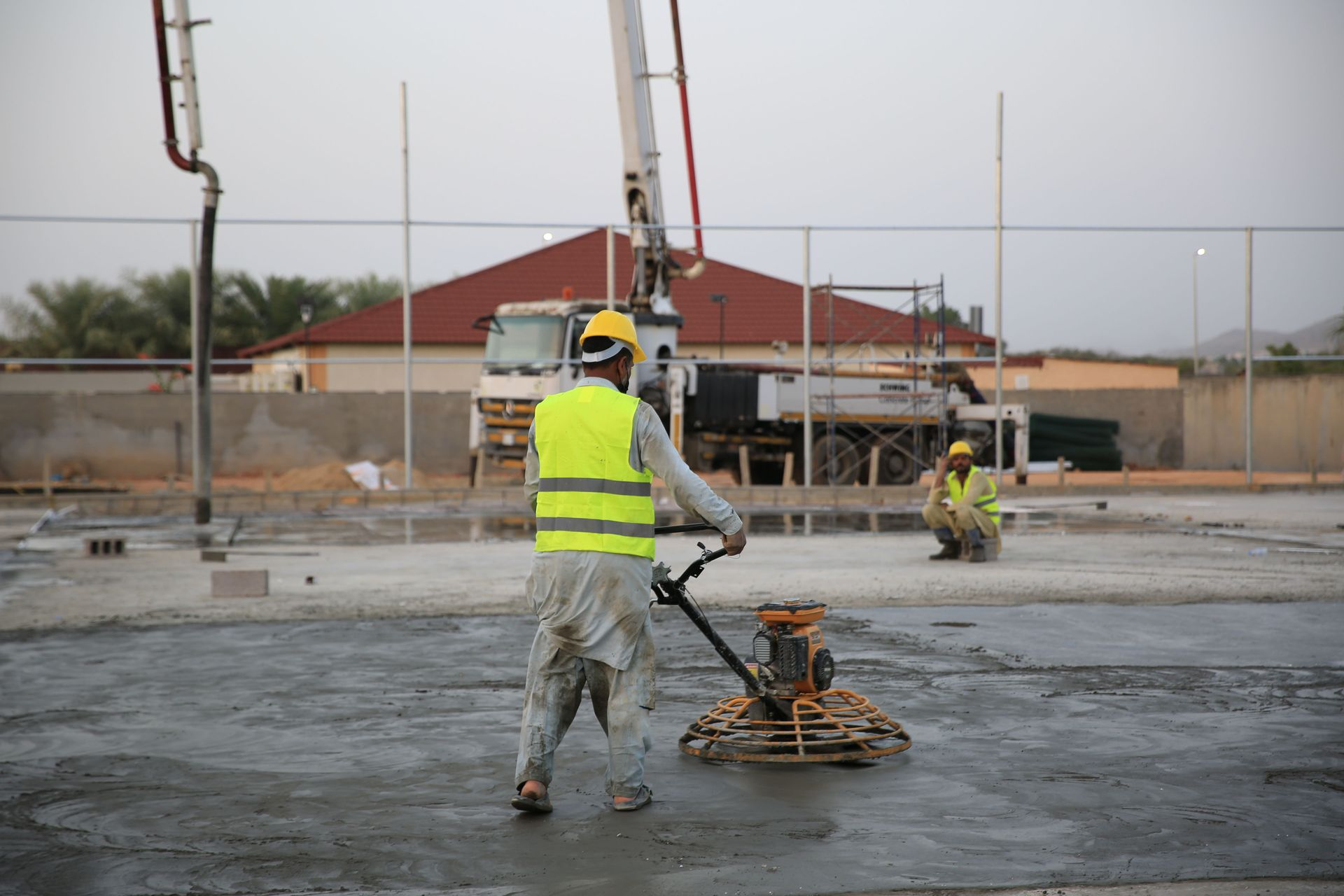 Construction workers smoothing wet concrete on a large slab at a building site