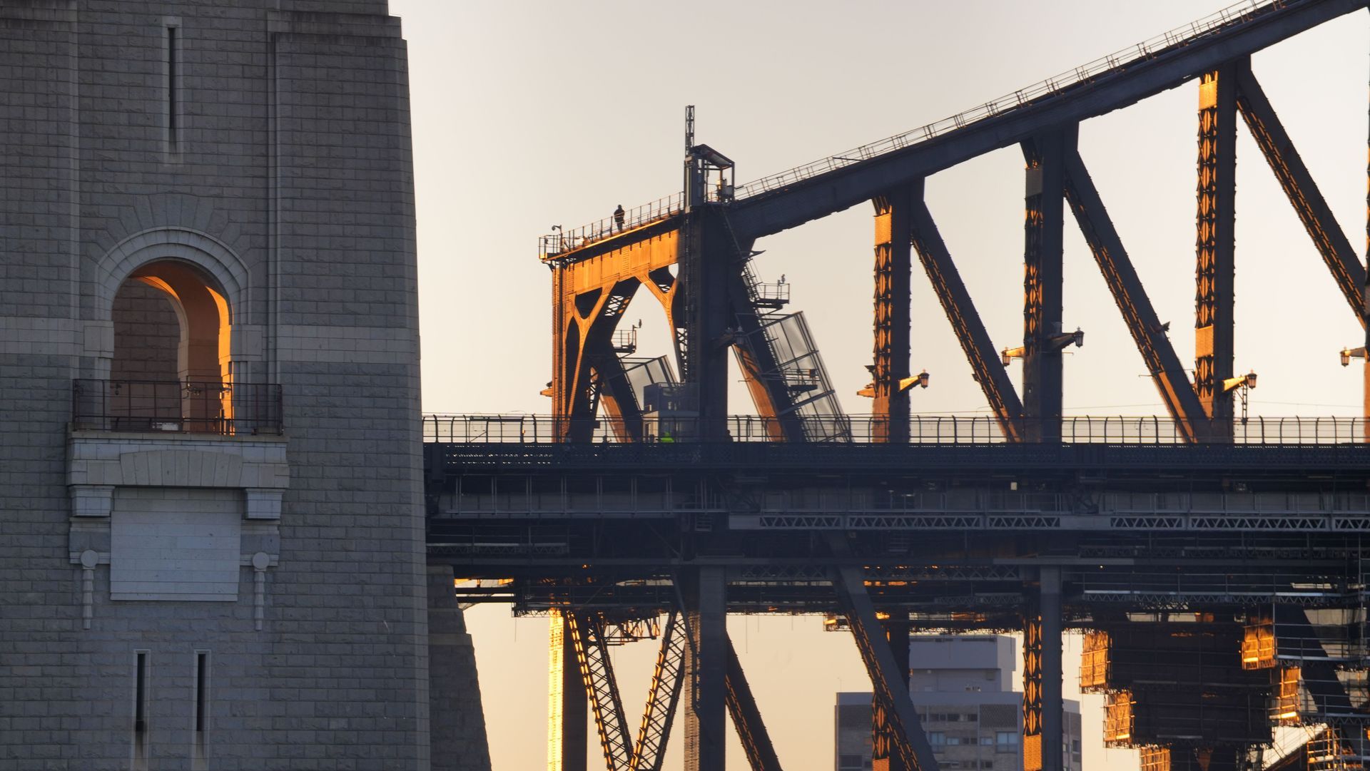 Urban street with tall yellow construction cranes between buildings under a clear blue sky