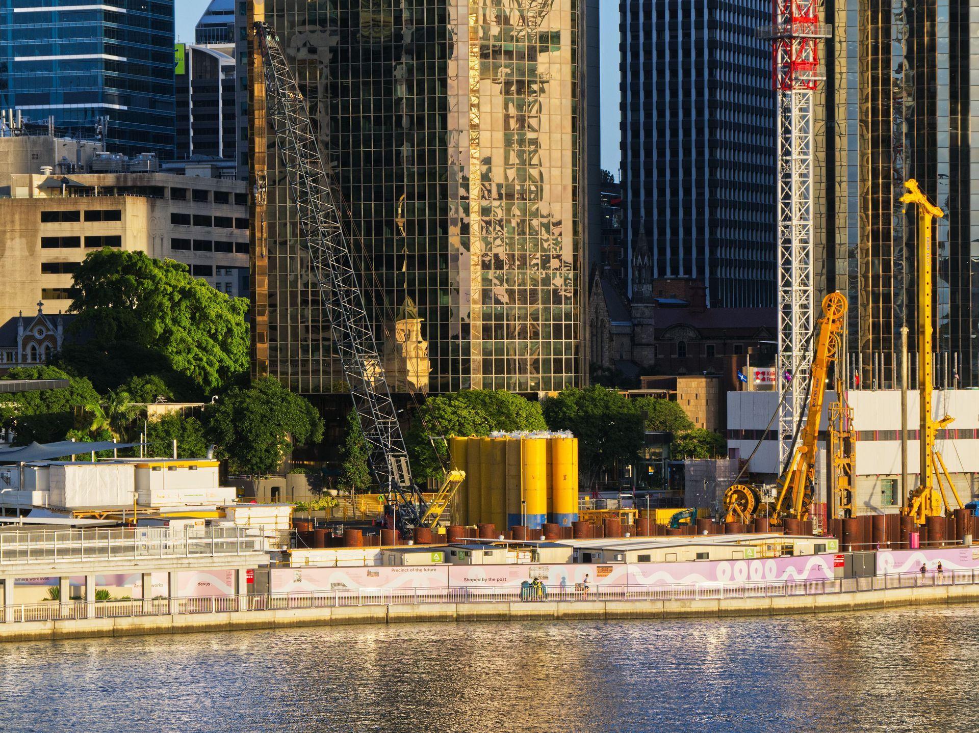 City skyline with tall buildings and a crane by the waterfront, with a boat on the river in Brisbane Australia