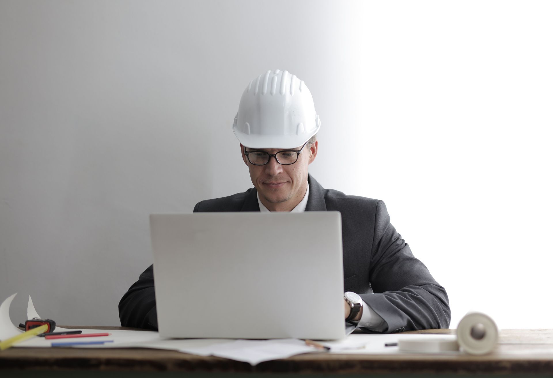 Engineer in a white hard hat working on a laptop at a desk