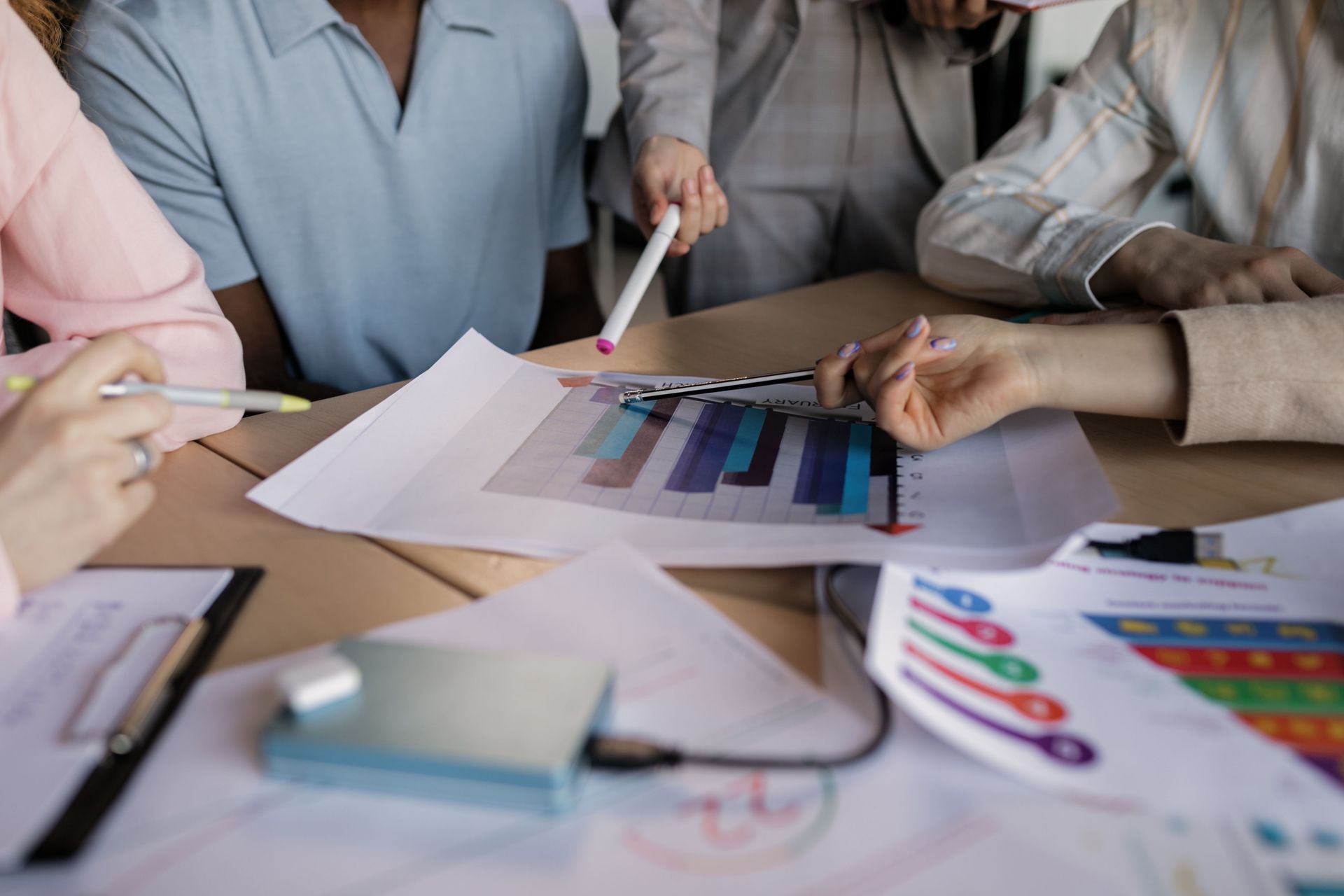 People collaborating at a table with color charts, documents, and pens during a meeting