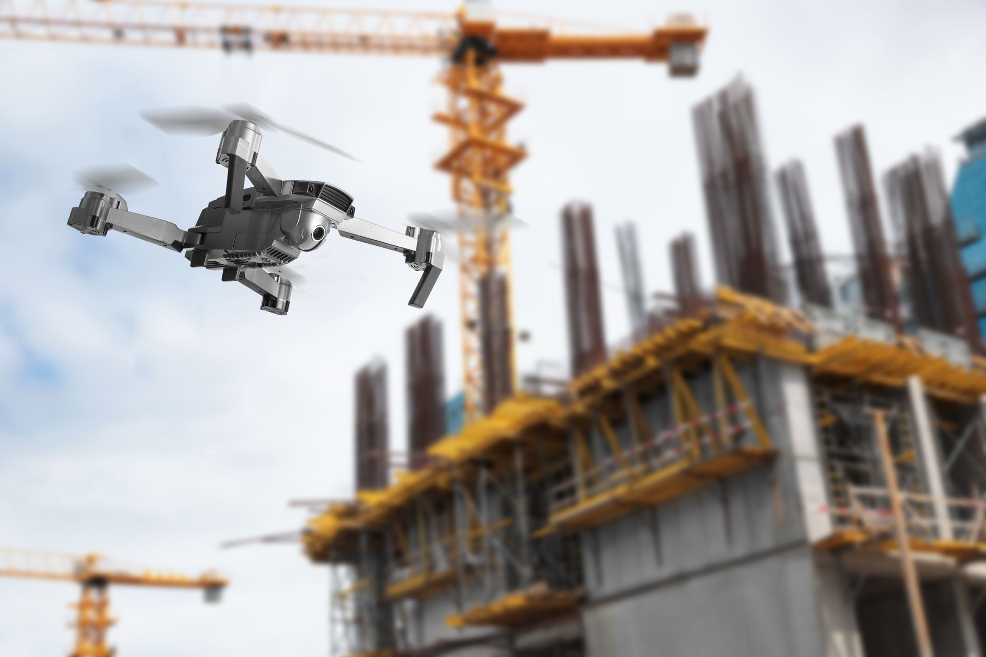 Drone flying near a construction site with cranes and concrete columns under construction