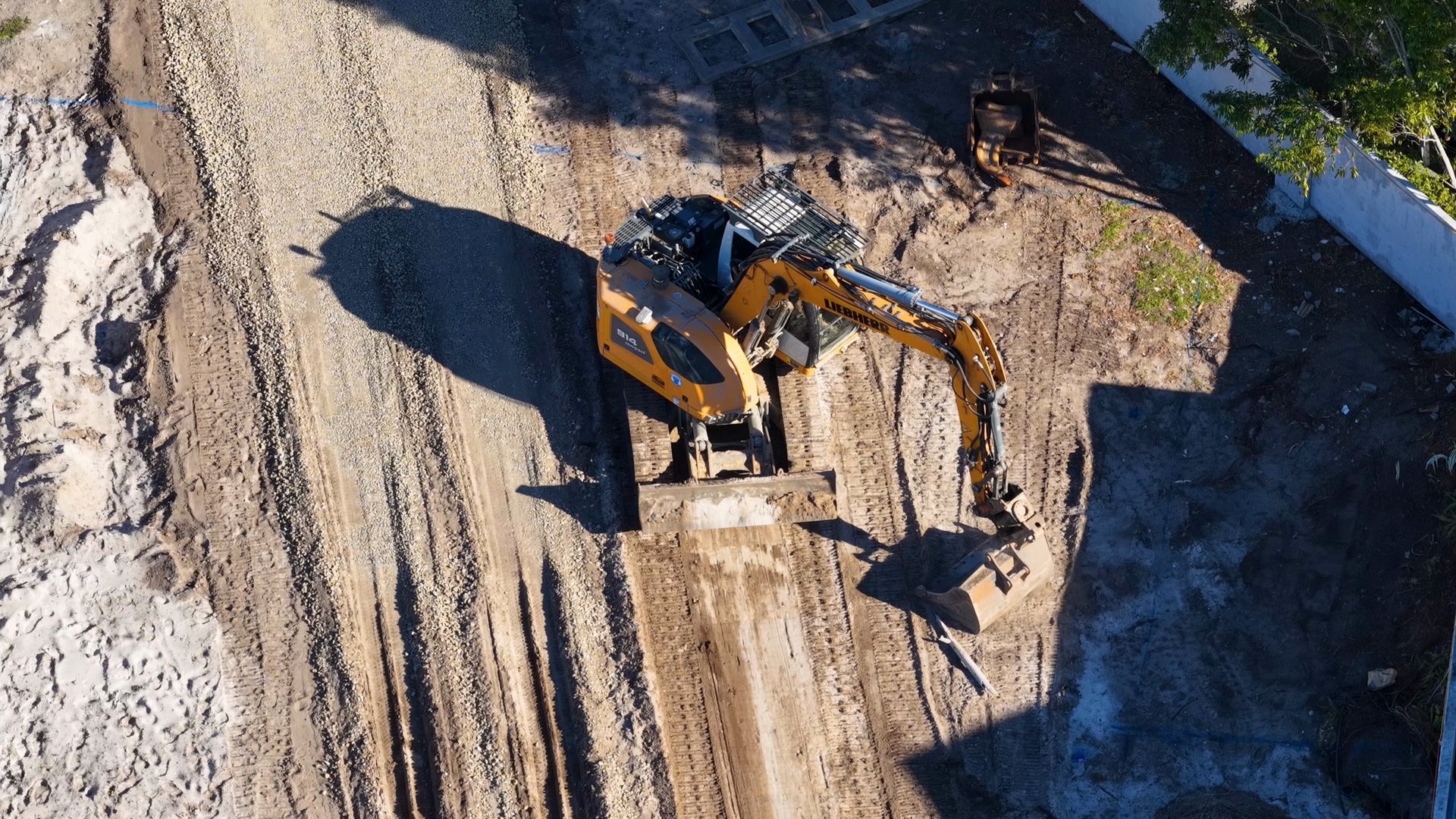 Yellow excavator digging dirt at a construction site beside a road