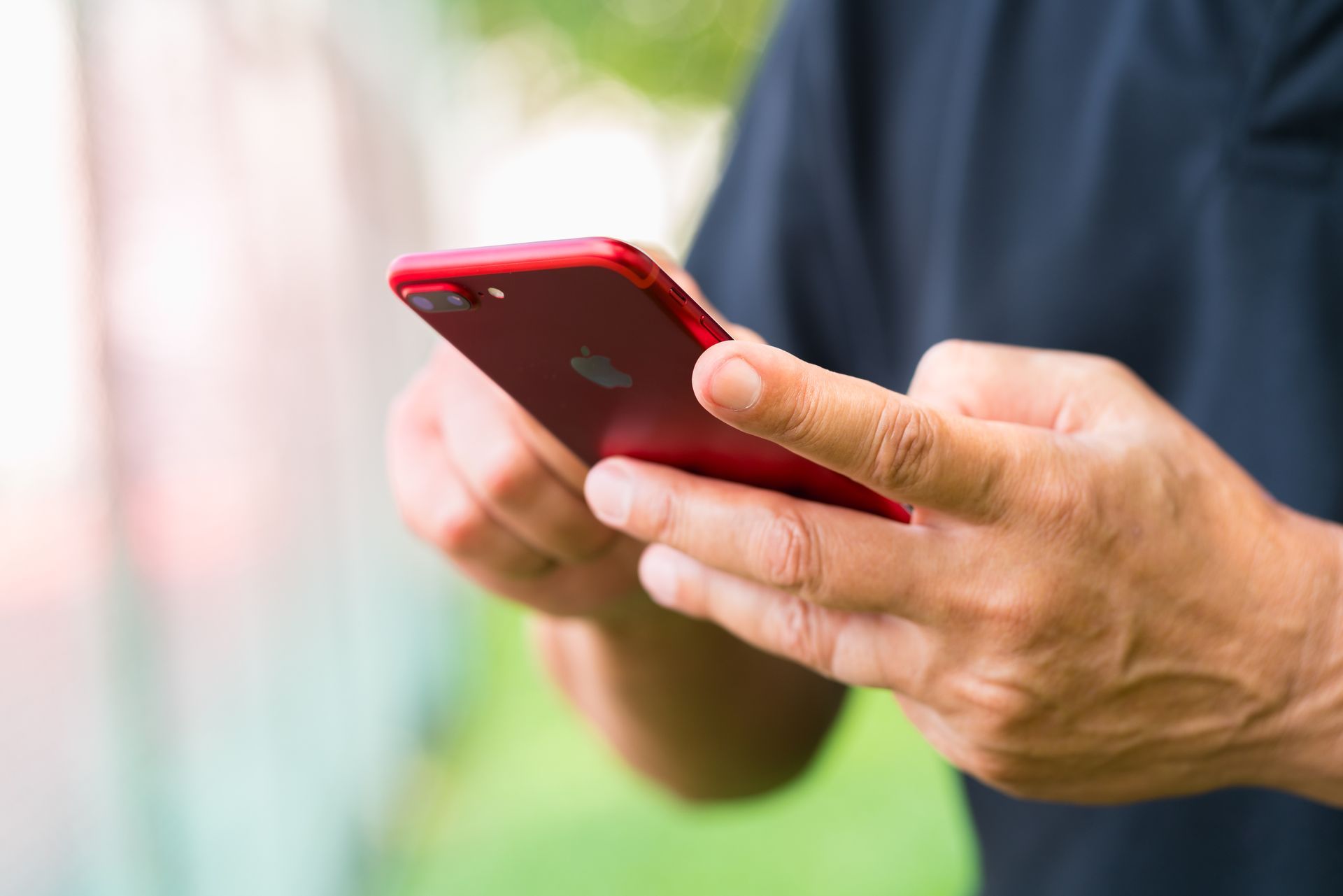 Person holding and looking at a smartphone at a workbench, with tools blurred in the background