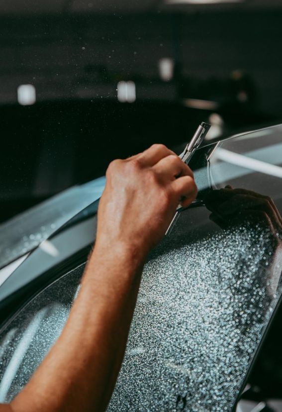 Person applying tint to car window with a squeegee.