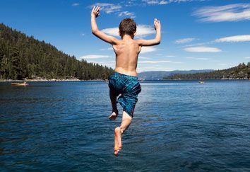 A young boy is jumping into a lake.