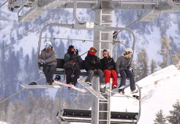 A group of people are riding a ski lift on a snowy mountain.