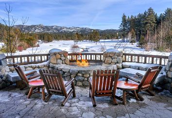 There is a fire pit on the patio with chairs around it.