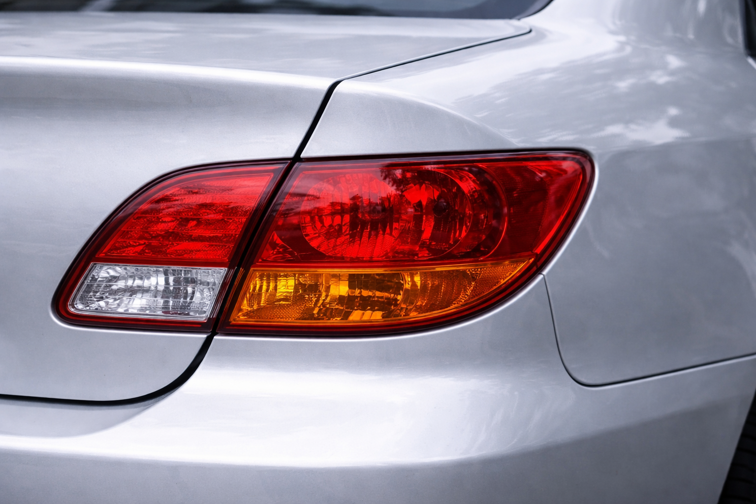 The silver rear exterior of a car, focusing on the red and amber taillight assembly.