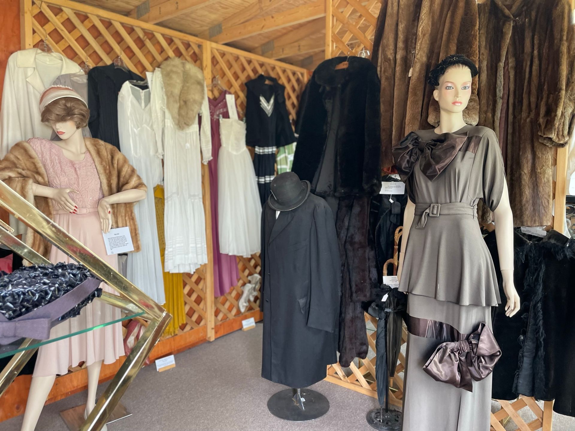 A mannequin is standing in front of a display of fur coats and dresses
