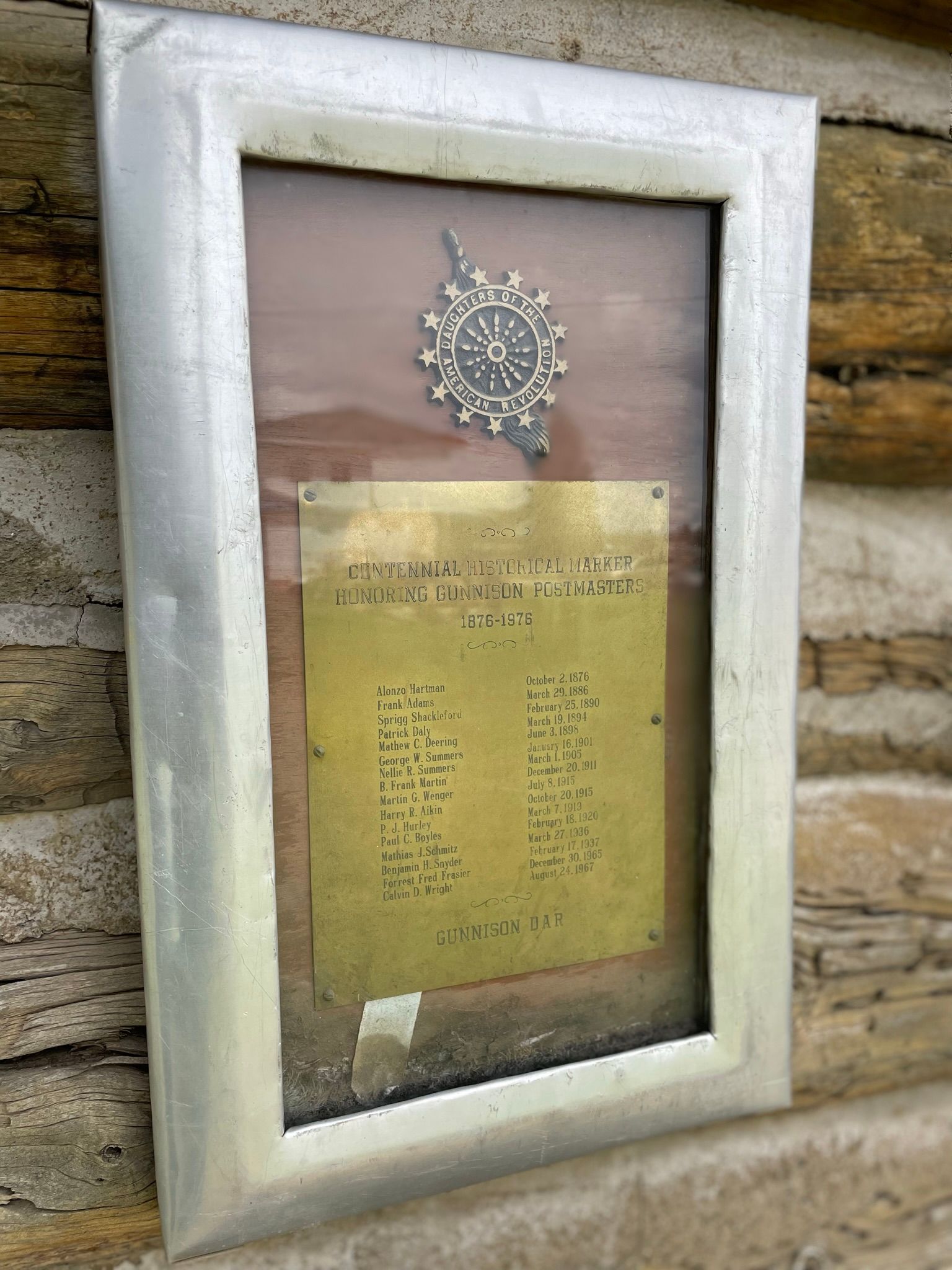 A picture frame with a clock on it is hanging on a wooden wall.