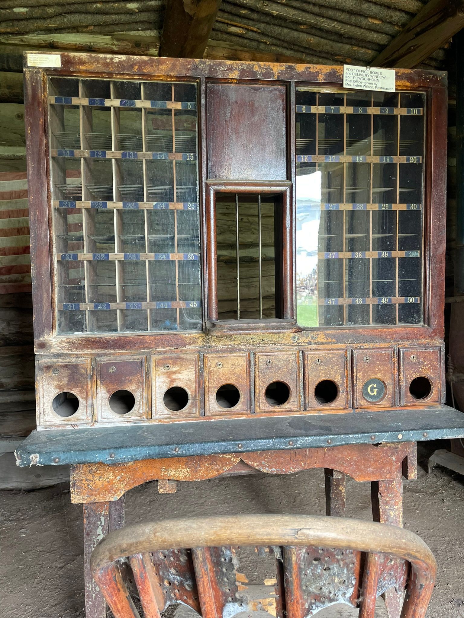 An old wooden cabinet with holes in it sits next to a chair
