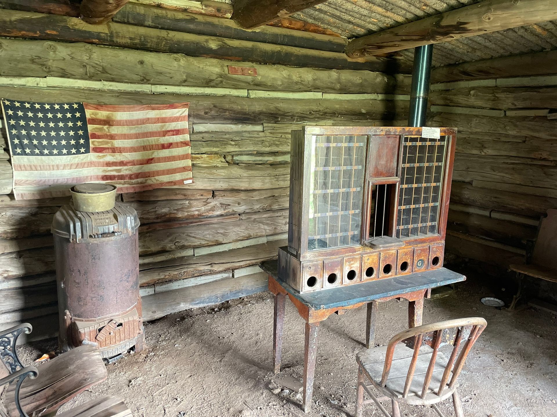 A wooden cabin with a table and chairs and an american flag on the wall.