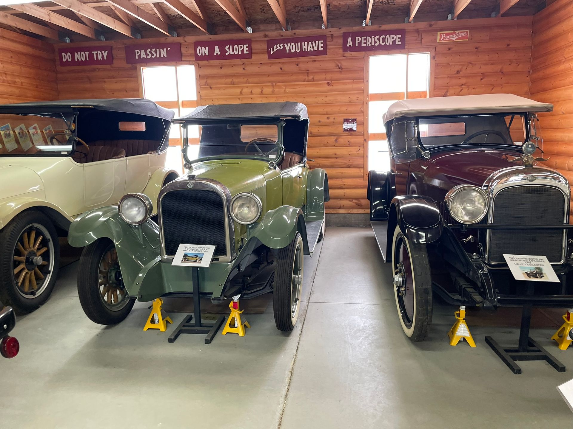 Three old cars are parked in a wooden garage