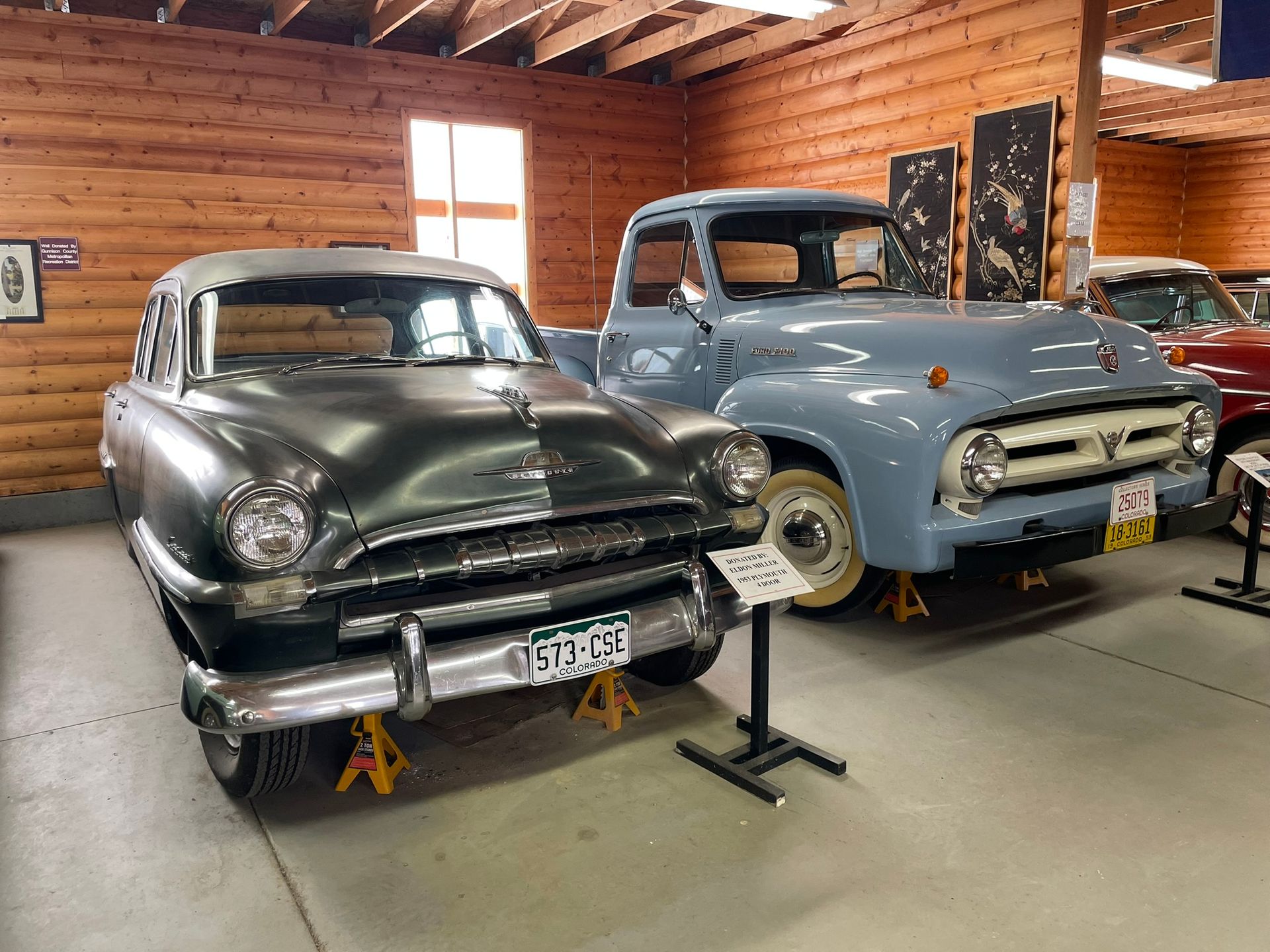 A black car and a blue truck are on display in a garage.