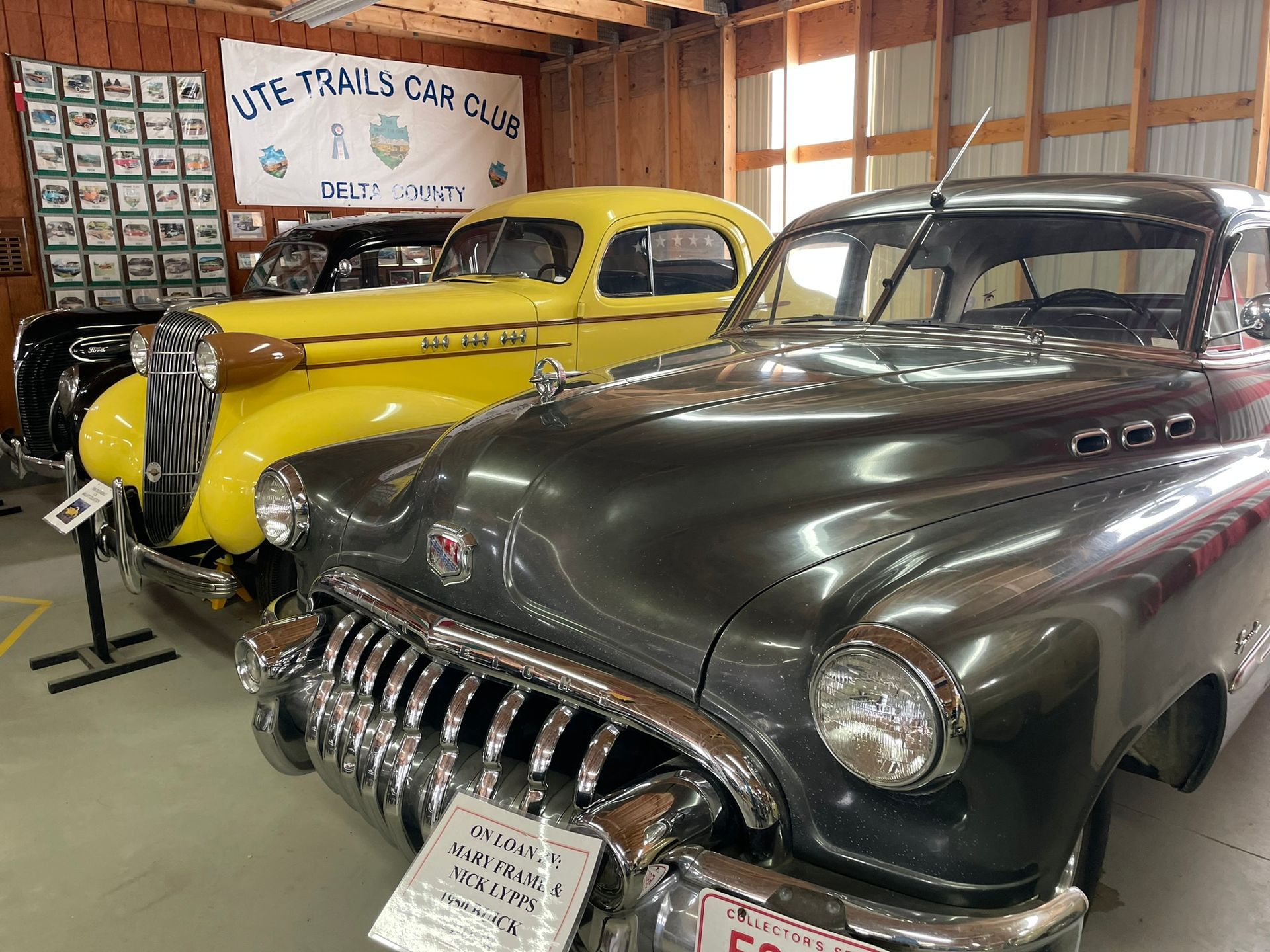 Two old cars are parked next to each other in a garage.