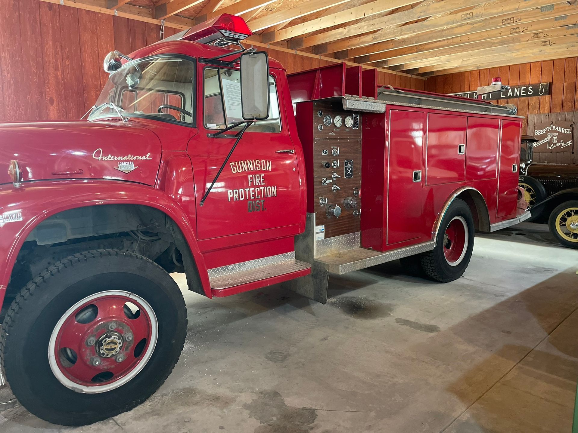 An old red fire truck is parked in a garage.