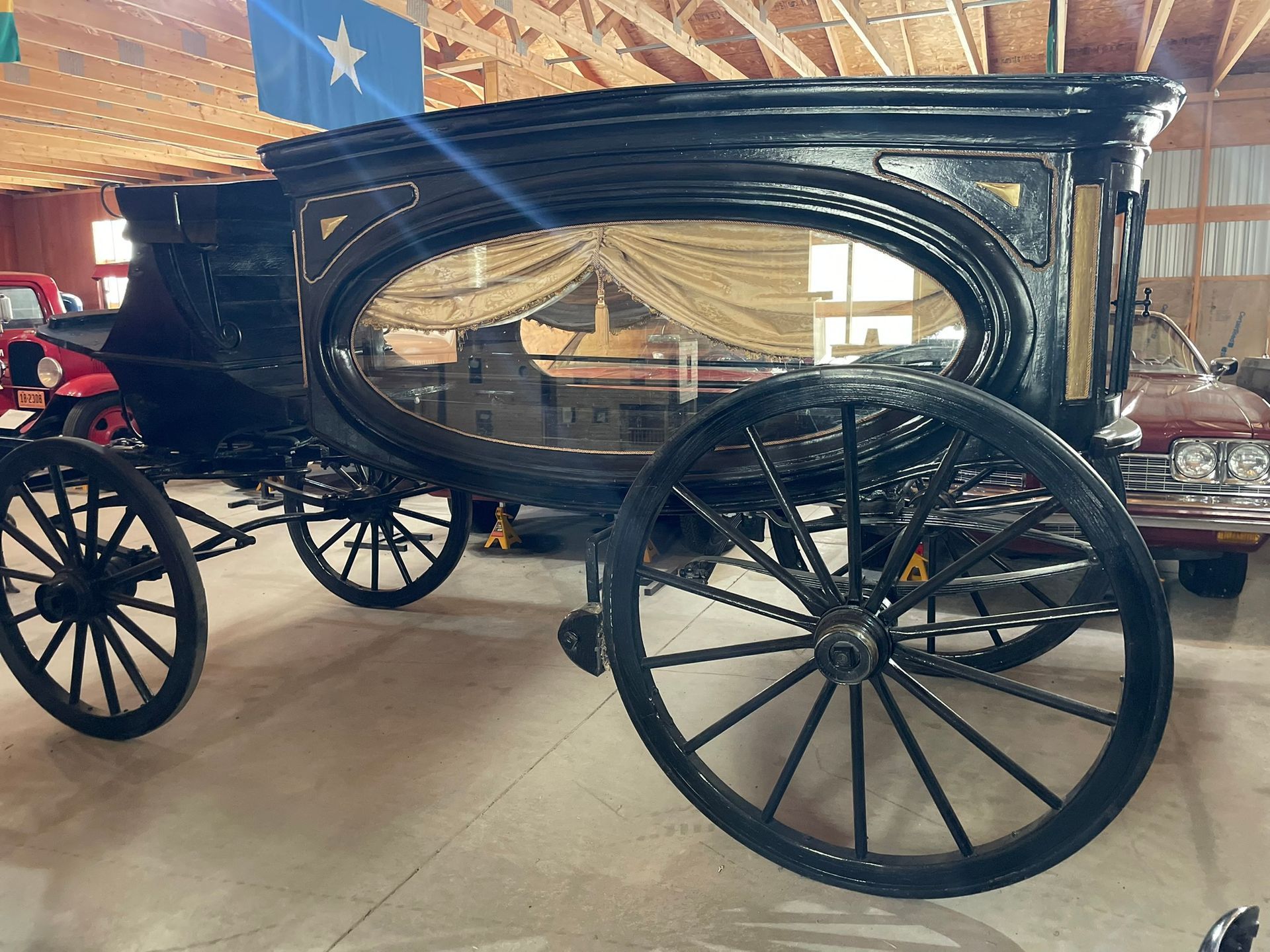A black carriage with a blue star on the side is parked in a garage.