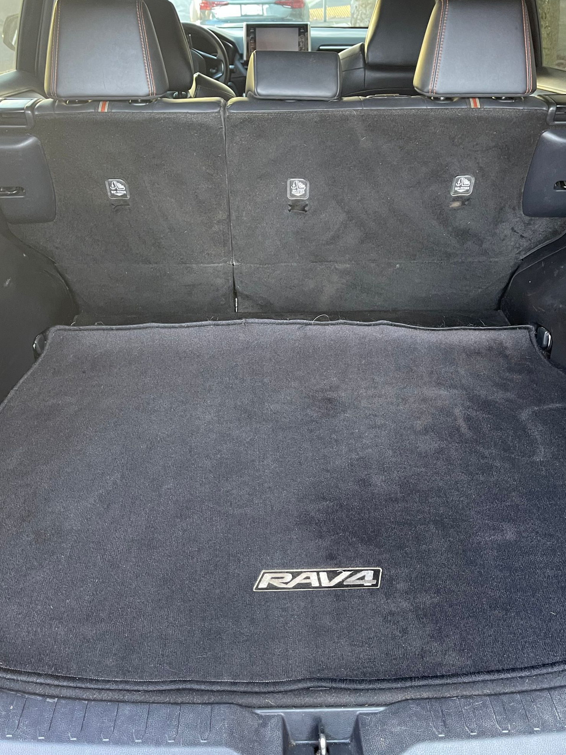 Rear cargo area of a vehicle with black carpeted floor mats and folded rear seats.