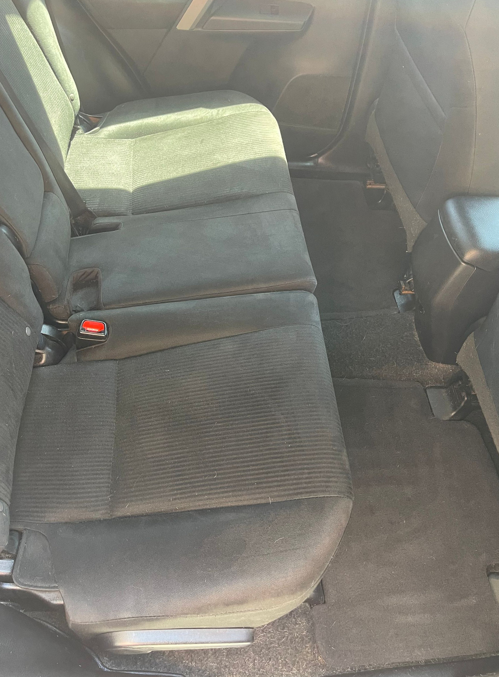 Car interior with black fabric rear seats and a red seatbelt buckle visible.