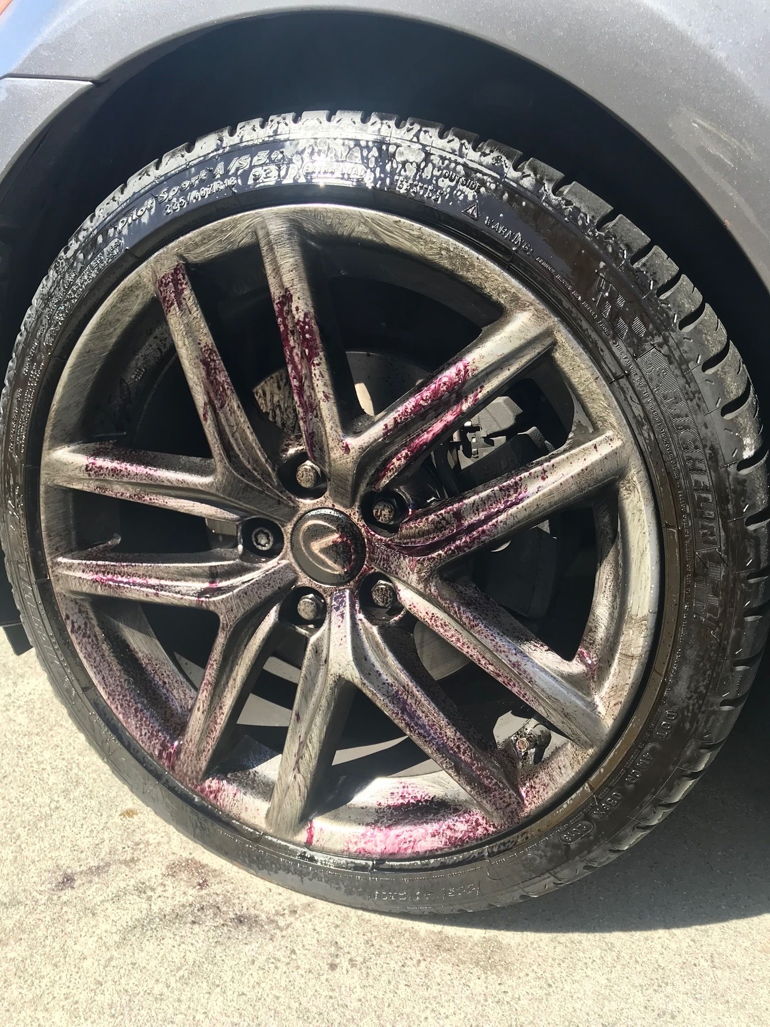 Close-up of a black alloy car wheel with white salt or snow residue on the tire