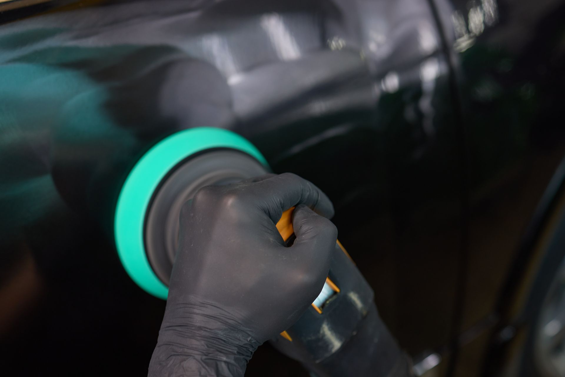 Gloved hand holding a hose nozzle with a glowing green ring, fueling a dark vehicle at night