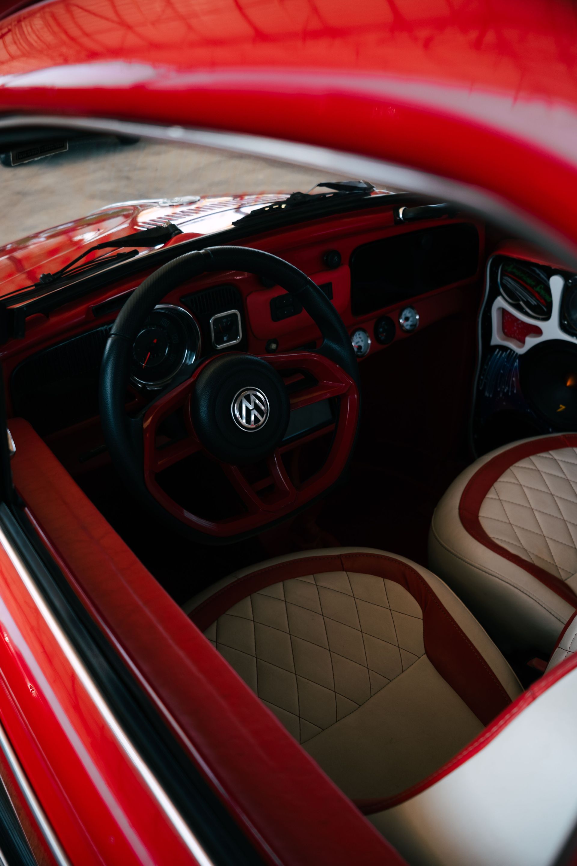 Red sports car interior with steering wheel, tan seats, and red trim through the open door