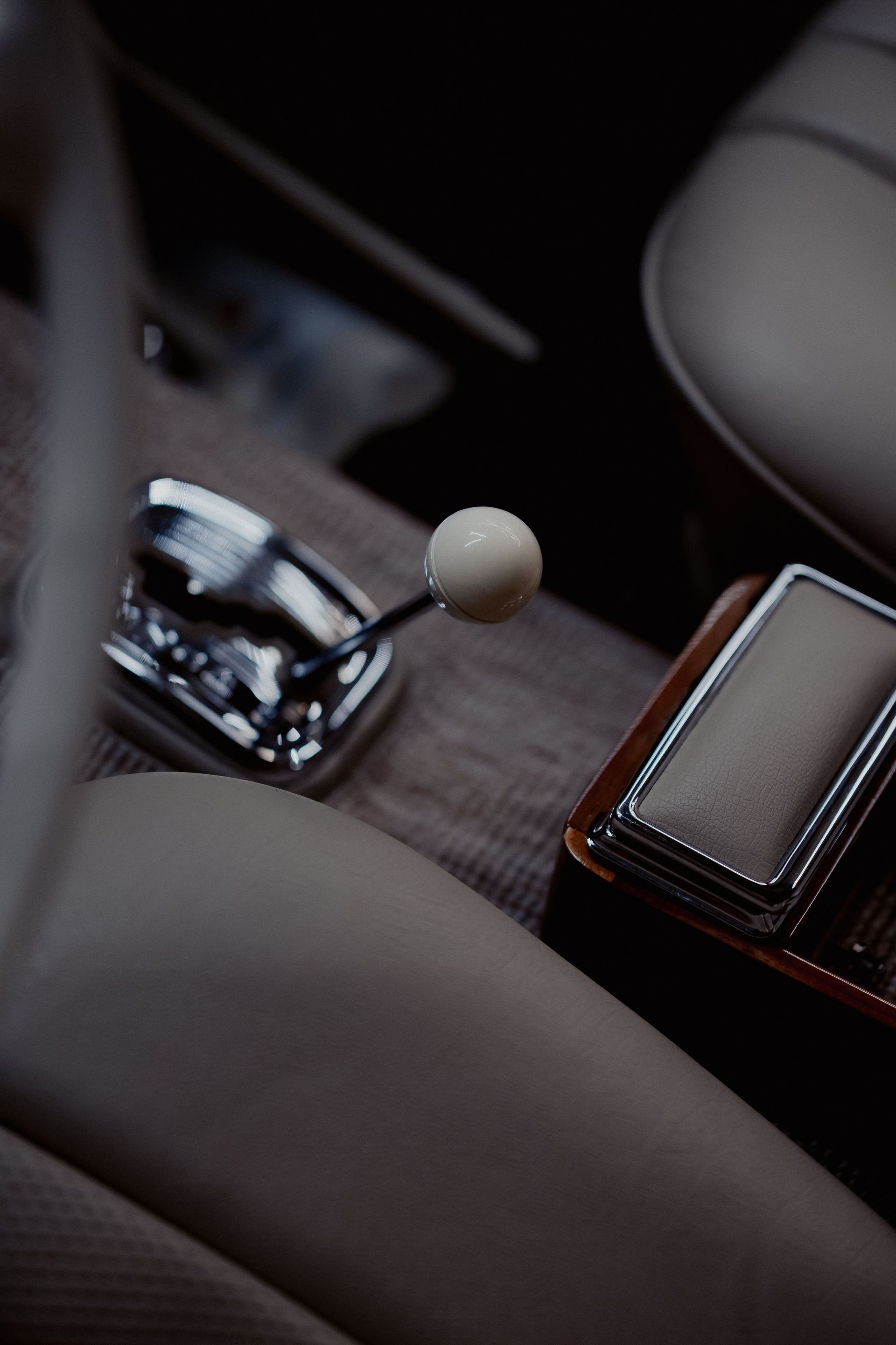 Car gear shift and cup holder beside a leather center console inside a car.