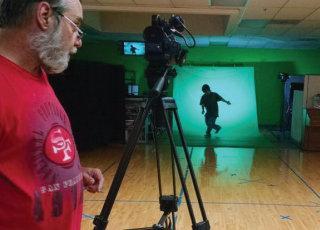 a man in a red shirt is standing in front of a green screen .