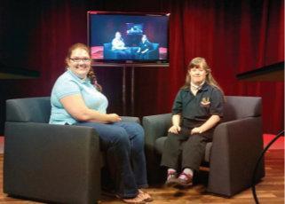 two women are sitting in chairs in front of a television .