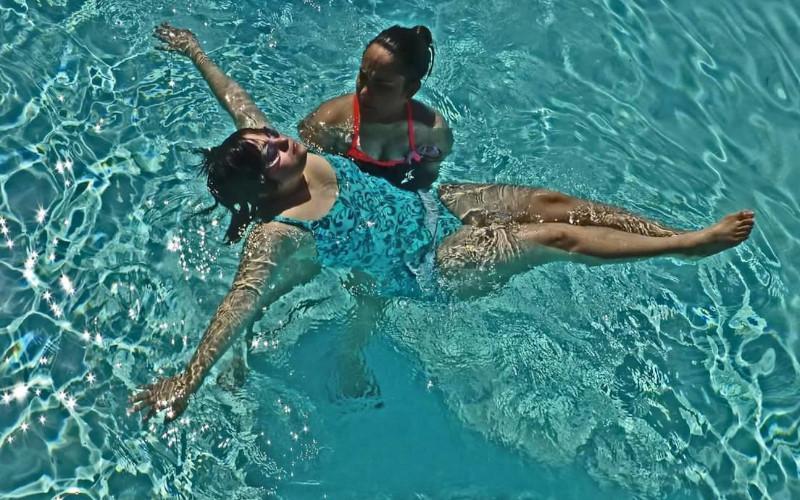 two women are floating on their backs in a swimming pool