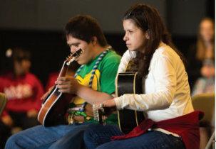 a man and a woman are sitting next to each other playing guitars .