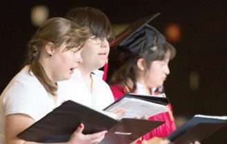 a group of graduates are singing in a choir at a graduation ceremony .