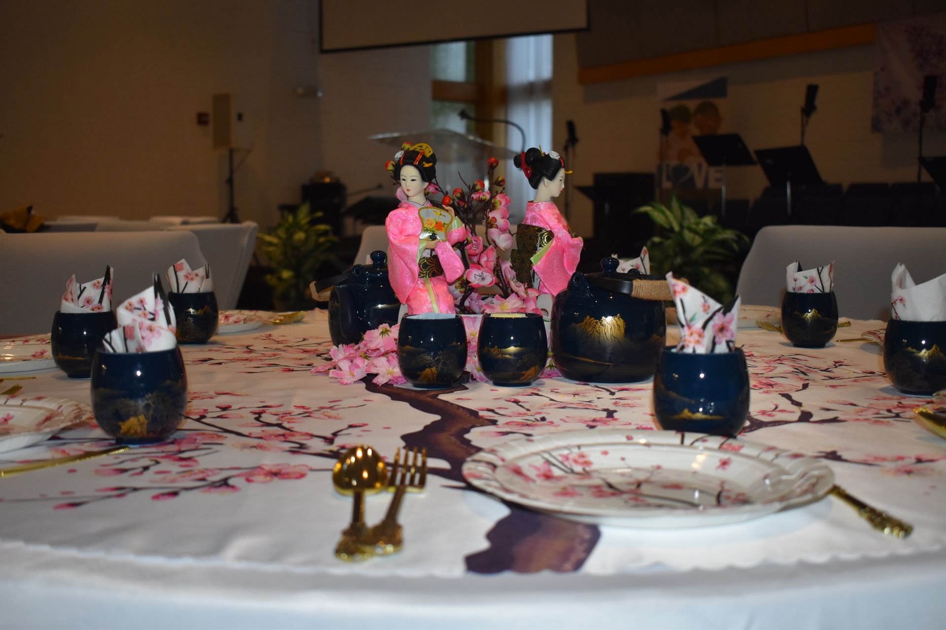 Decorated banquet table with floral centerpieces, candles, and place settings at an indoor event