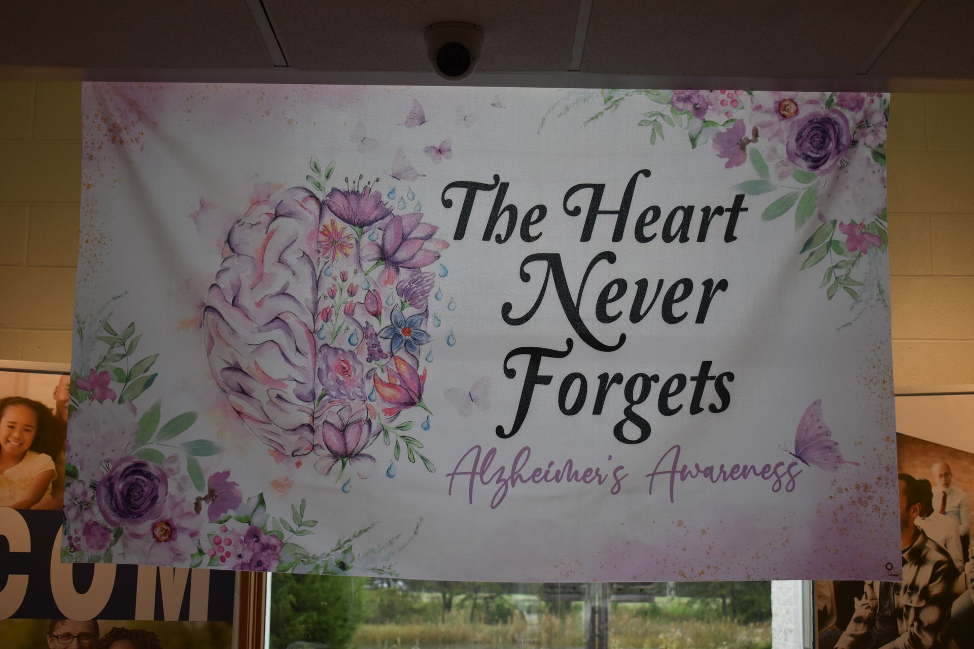 Banner reading “The Heart Never Forgets” with flowers and butterflies on a pastel floral background