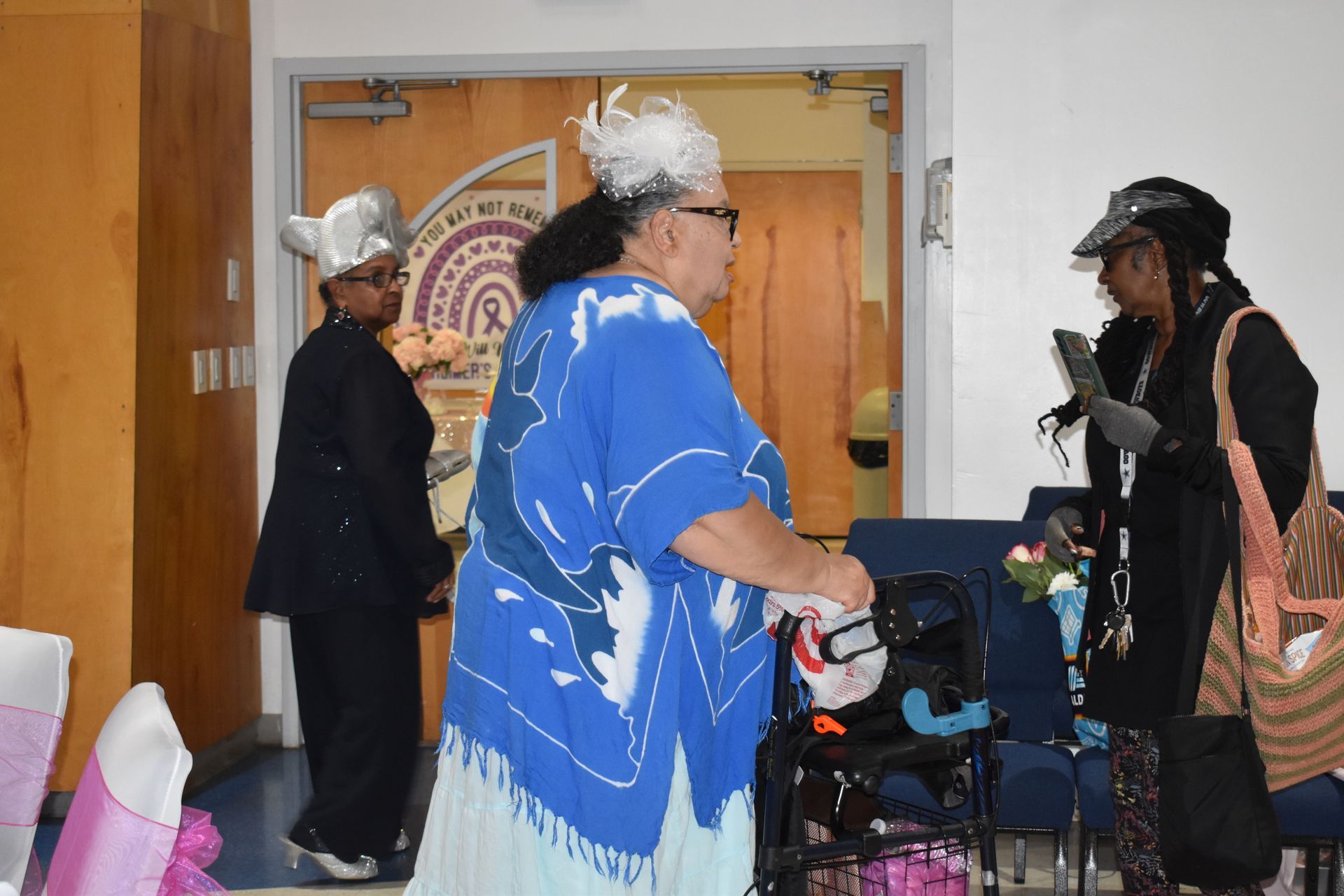 People in costumes talking beside a stroller in a hallway with a large circular wall sign