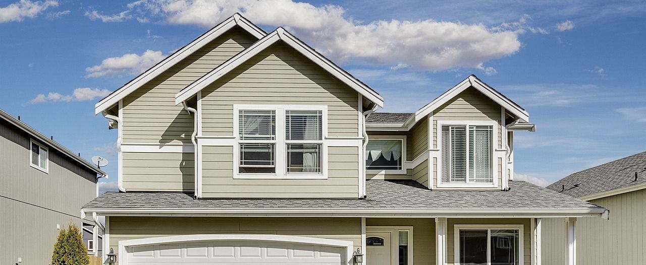A large house with a garage and a blue sky in the background.