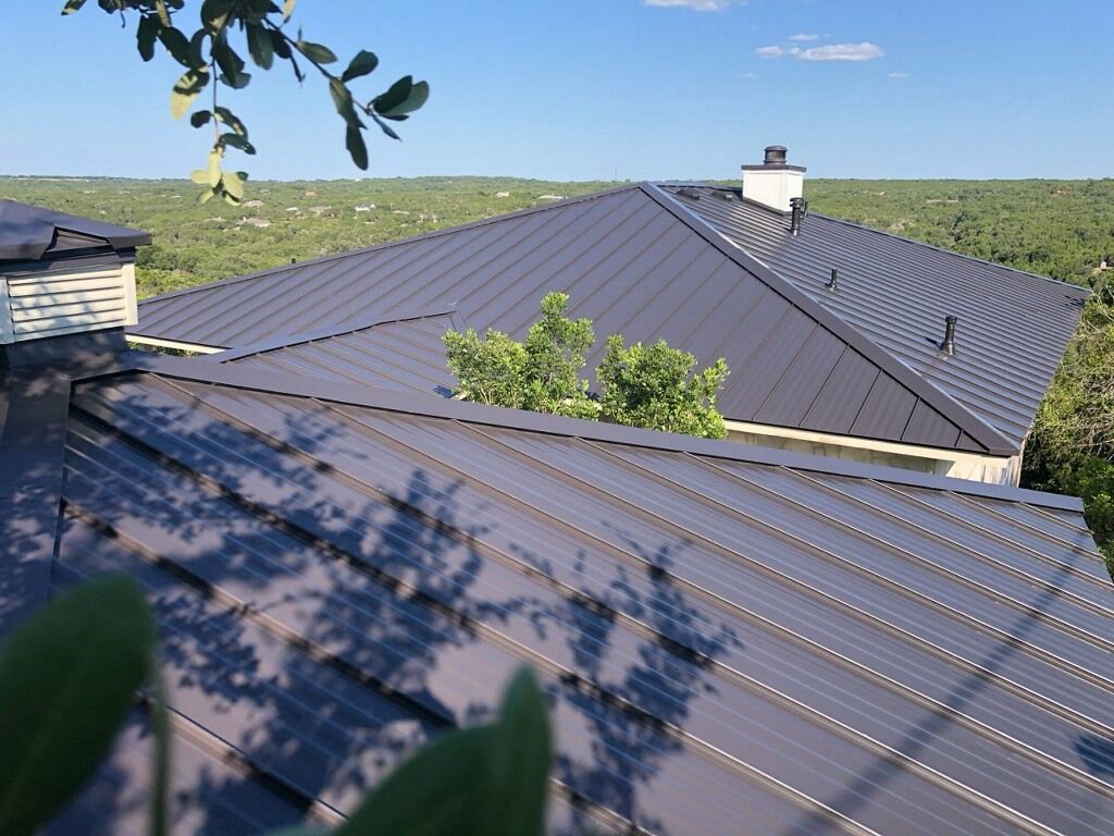 The roof of a house with a metal roof and a chimney.