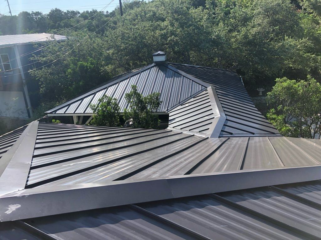 A close up of a metal roof with trees in the background.