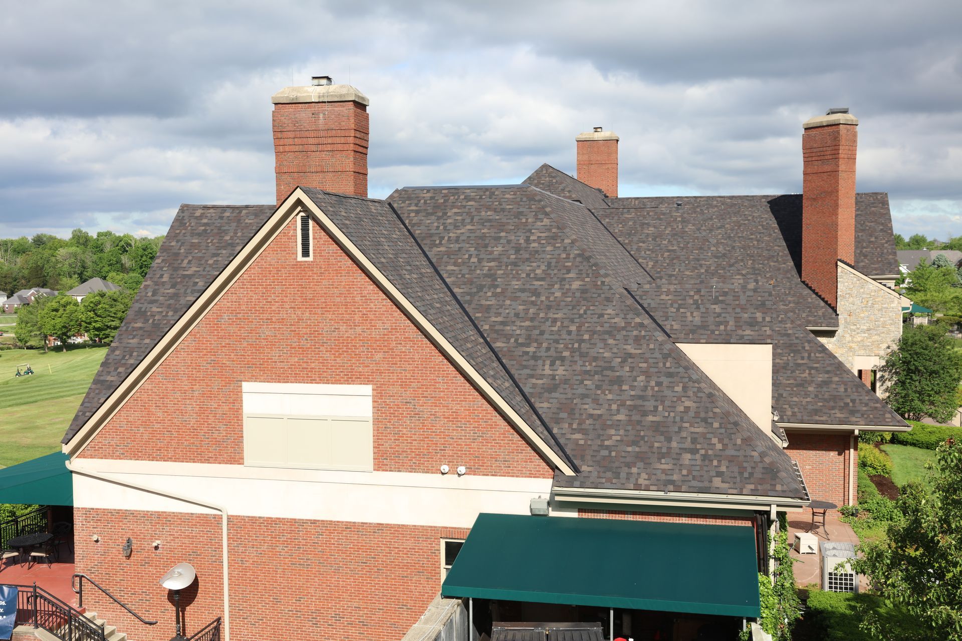 A large brick house with a black roof and chimneys