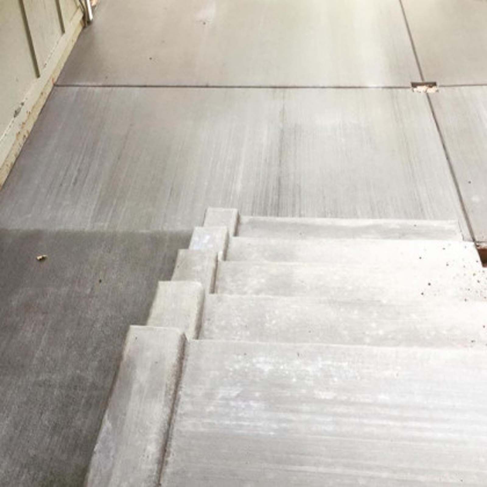 Concrete stairs leading down to a paved outdoor patio area.
