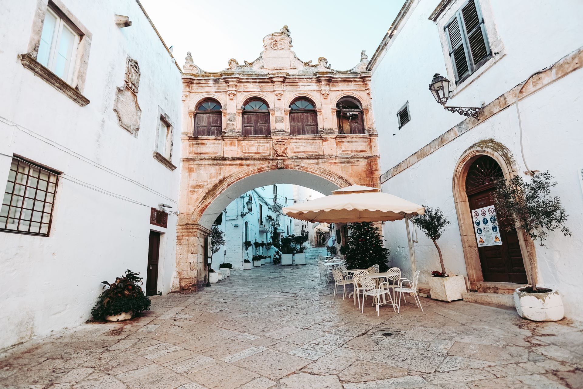 A aerial view of Ostuni showing the picturesque white-washed buildings and winding cobblestone streets, the stunning countryside can also be seen in the background with Olive trees plantation