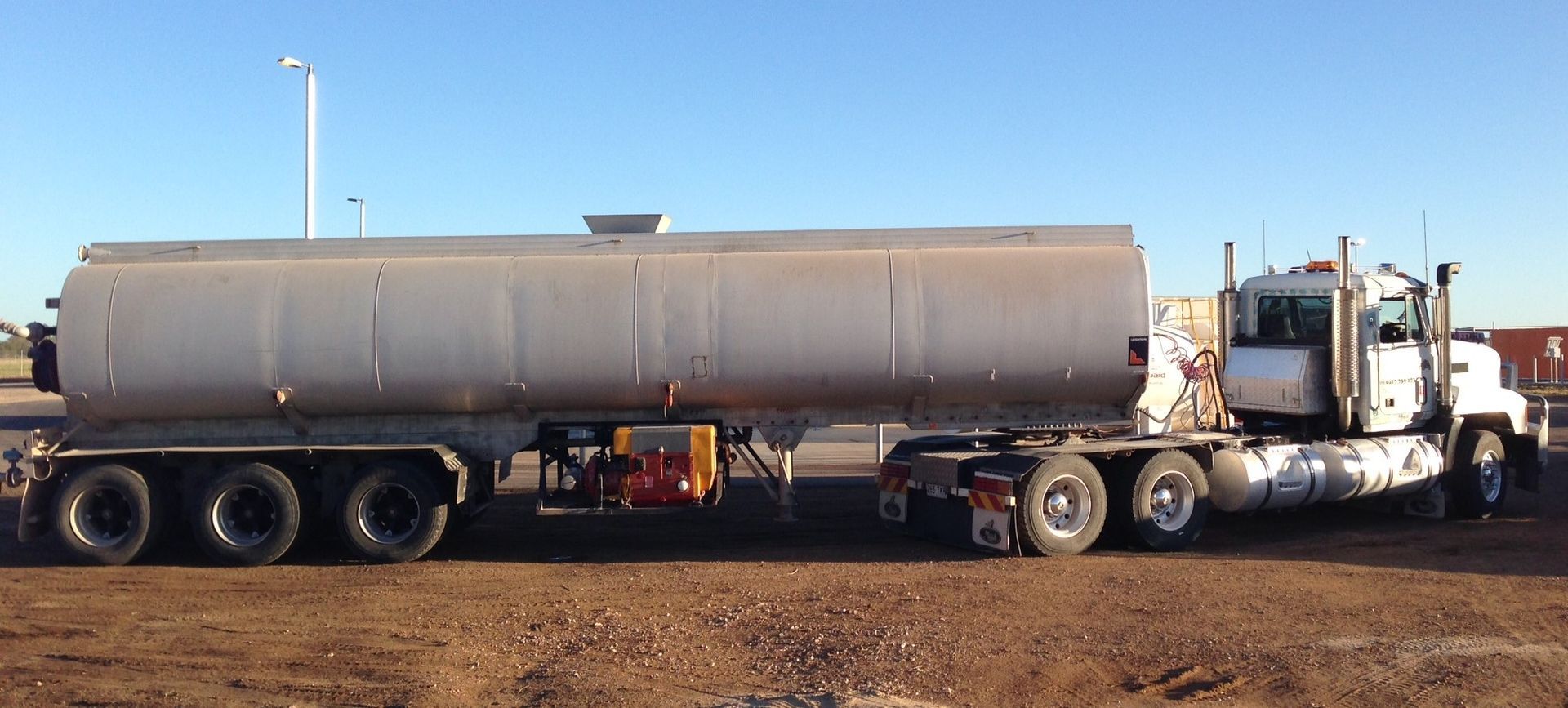 A large tanker truck parked on a dirt lot against a clear blue sky — Chewies Tipper Hire & Haulage in Gracemere, QLD