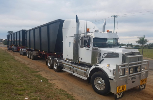 White Semi-truck With Two Black Trailers On A Dirt Road — Chewies Tipper Hire & Haulage in Gracemere, QLD