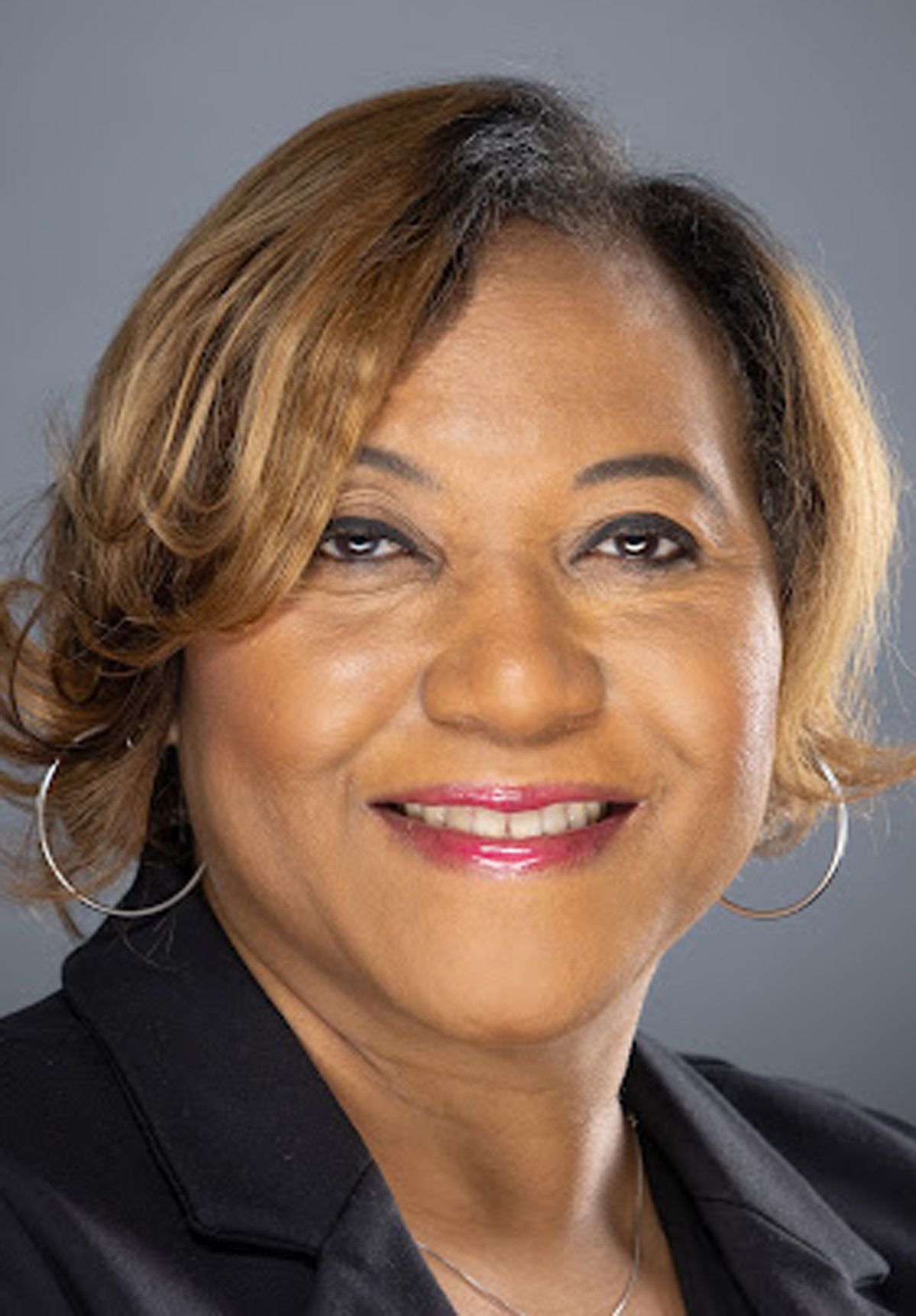 Smiling woman in a black blazer against a gray background