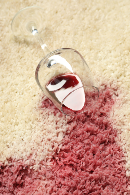 A glass of wine has spilled on a carpet.